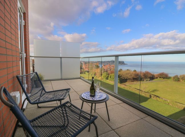 A balcony with chairs and a table overlooking the sea at The Lookout 