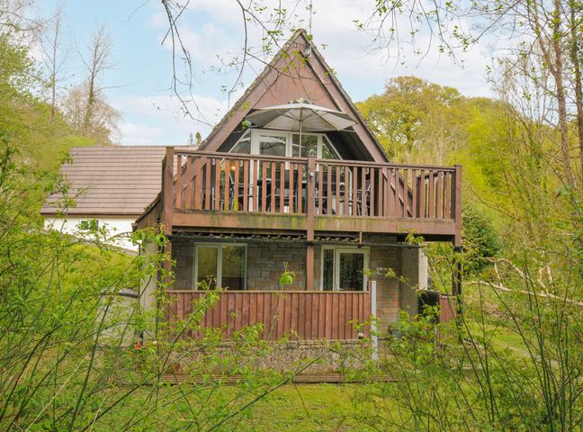 A house with a balcony and trees surrounding it at Hideaway Cottage, St Ann's Chapel, Cornwall