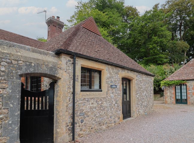 An exterior view of a stone cottage with a door and window at Yard Cottage Rousdon