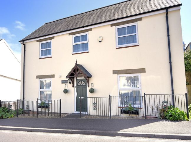 A two story house with four windows a green door and metal railings at Vine Cottage in Charmouth