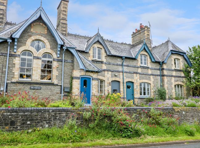 Stone terrace houses with blue doors windows and flower gardens in front at Teachers Cottage Presteigne
