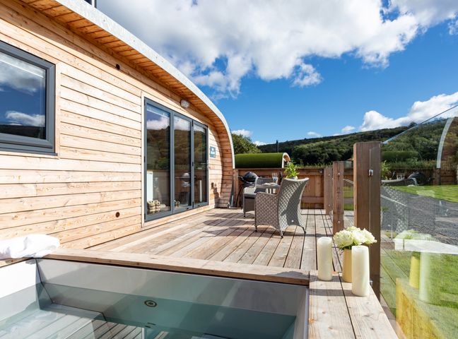 A wooden deck with outdoor seating and a hot tub at High Longlands in Cartmel