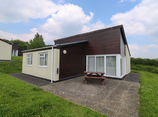 A bungalow with a patio and picnic table on a grassy lawn at Harcombe House Bungalow 11 in Chudleigh
