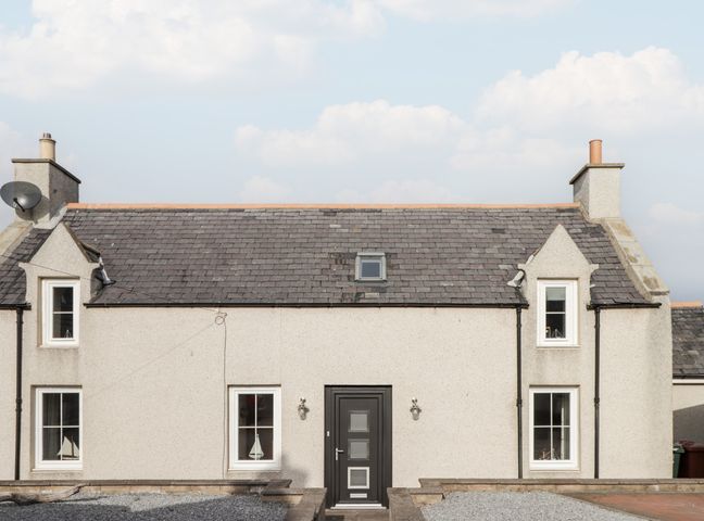 A two-story house with a black front door four windows a tiled roof and two chimneys at Learig in Buckie