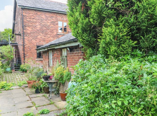 An outdoor garden area with potted plants and a brick building with windows at The Toolshed in Birchwood
