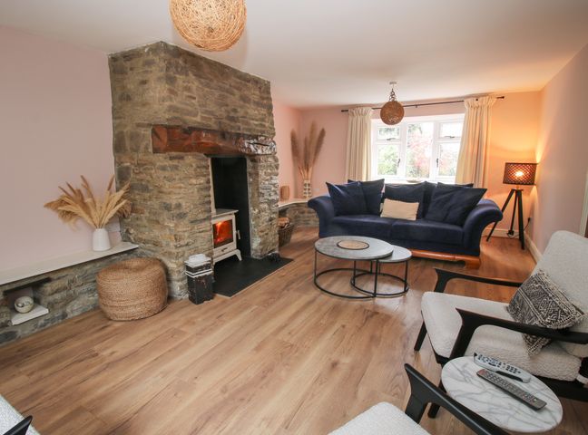 A living room with a stone fireplace a blue sofa a pair of chairs and a coffee table at Laurgeths House in Bishops Castle