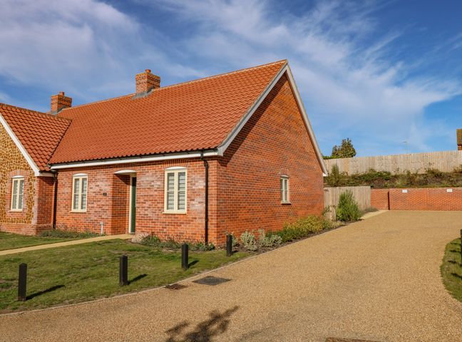 A brick house with a tiled roof and paved driveway at Woodpecker in Hunstanton