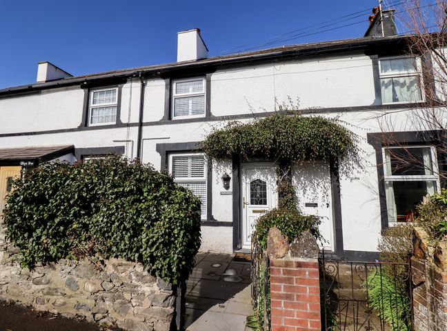 A white house with black trim and a small garden with green bushes at Glynside in Conwy