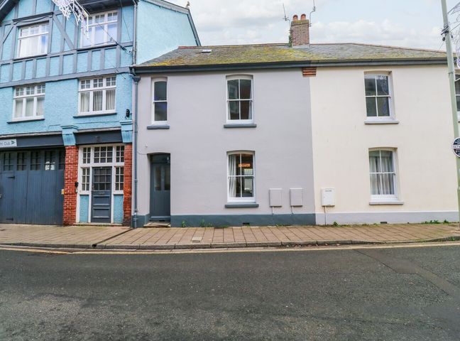 A row of attached houses with different painted exteriors and windows along a paved sidewalk on a street at Green Retreat in Dartmouth