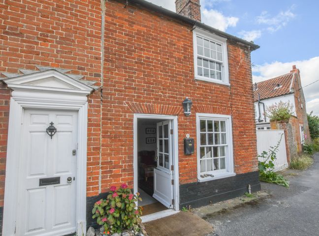 The exterior of a brick house with a white door and an open white porch door with a black mailbox at 17 South Green Southwold