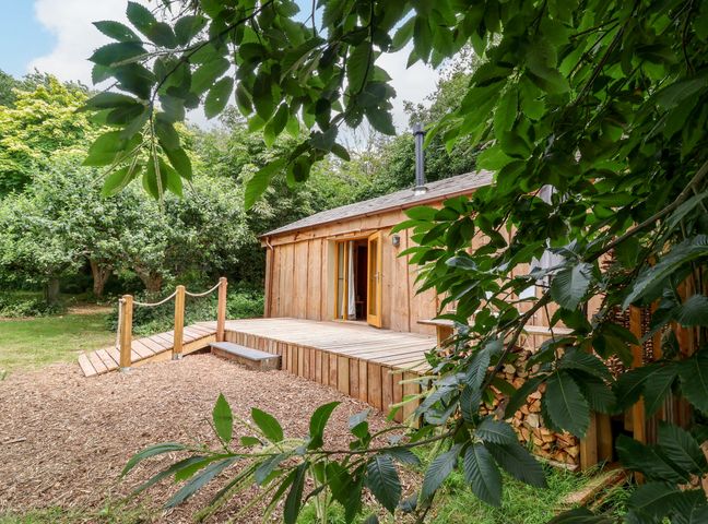 A wooden cabin with a deck and entrance at Brambly Cabin in Crediton