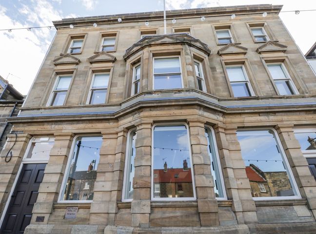 Stone building with large windows and string lights at Lewis Hunton Suite in Loftus