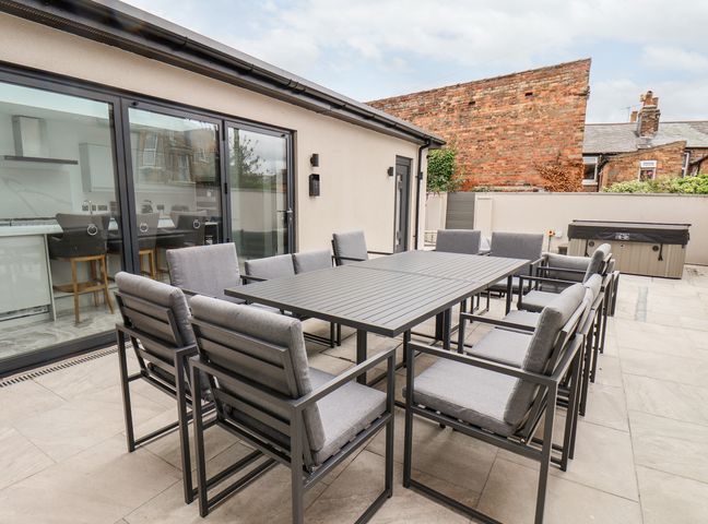 An outdoor patio area with a large rectangular table and twelve cushioned chairs at Church View Scarborough