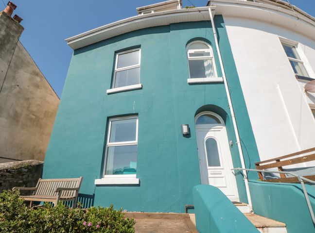 Blue and white two-story house exterior with windows door bench and plants at 2 North Furzeham Road Brixham
