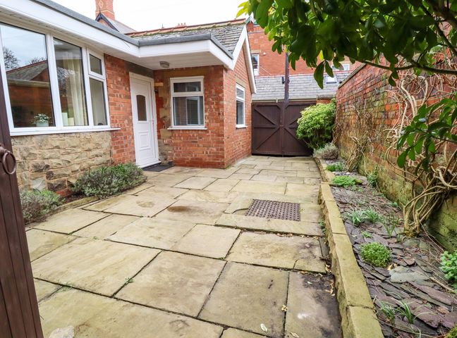 A paved courtyard with brick walls and a wooden gate at Jasmine Cottage in Lytham St Annes