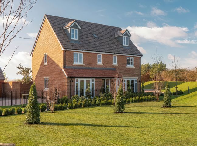 A brick house with a large green lawn and small trees at Goodwood Retreat in Chichester