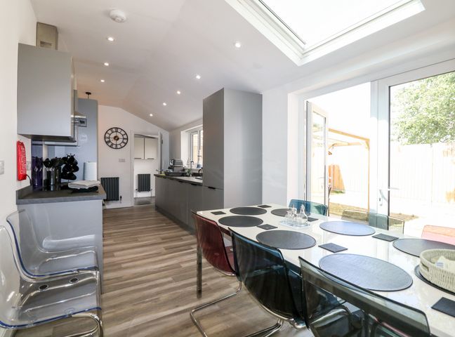 A kitchen with a dining table and transparent chairs near a window at The Beach House in Mablethorpe