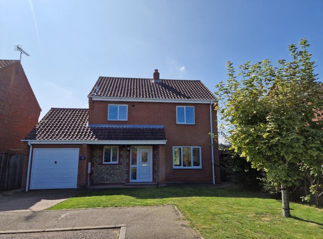 A two-story brick house with a tiled roof a garage a front door and a tree on the lawn at Field View in Bodham near Sheringham