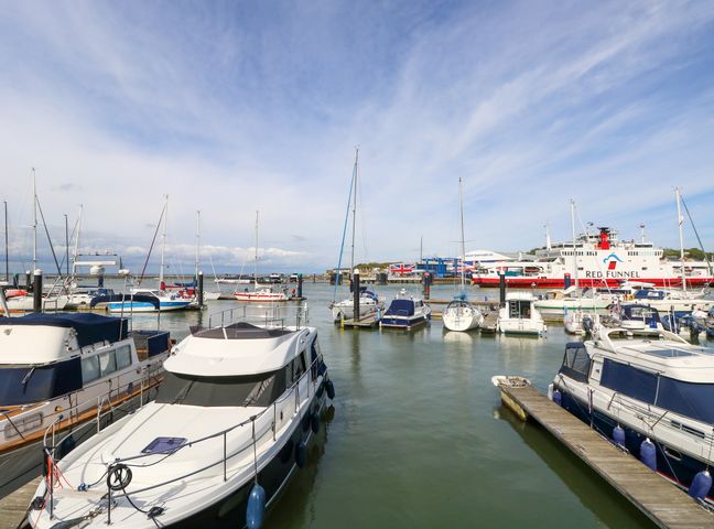 A marina with various boats and a large ferry with red funnel in the background at Marina View in Cowes