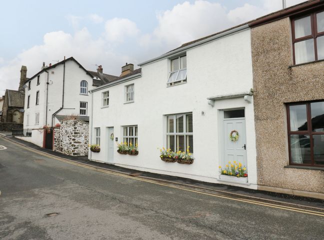 A street with houses featuring white walls and flower boxes under windows and doors at The Anvil in Broughton-In-Furness