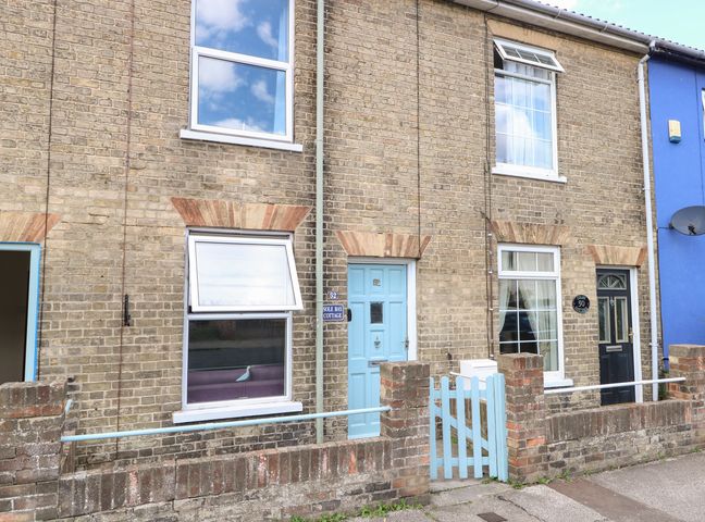 A brick terrace house with blue door and gate and windows showing curtains at Sole Bay Cottage in Lowestoft