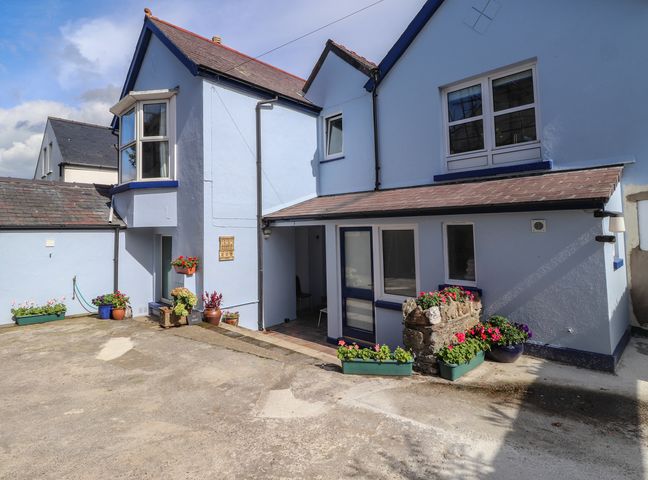 Exterior of a light blue painted house with flower pots around the entrance at Ty Post Newport Pembrokeshire