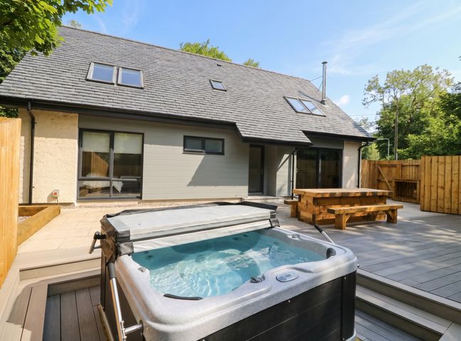 An outdoor area with a hot tub and wooden table at Nevis Bridge House in Fort William