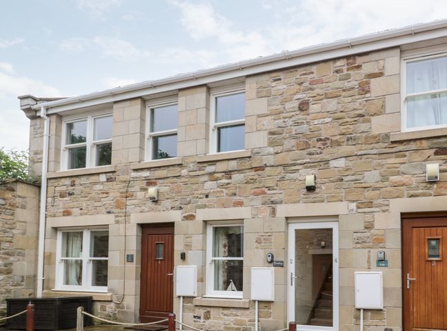 A stone house with multiple windows and wooden doors at 2 Apple Tree in Beadnell