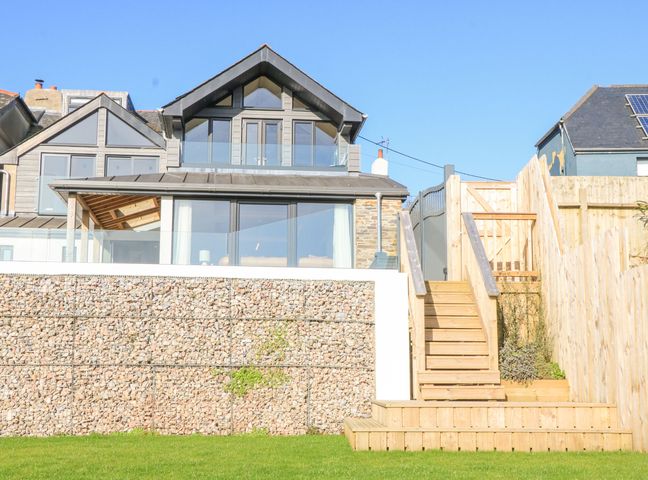 A modern house with glass balcony stone wall wooden stairs and fenced garden at Oakleigh in Blackawton