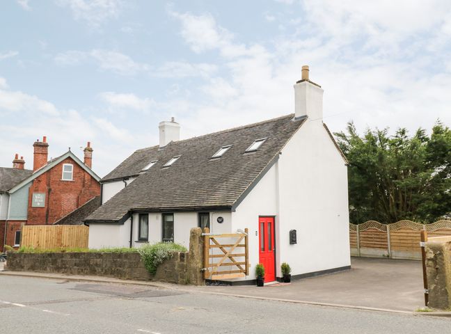 A white house with a red door and a wooden gate beside a road at Valley View in Hulland Ward near Ashbourne