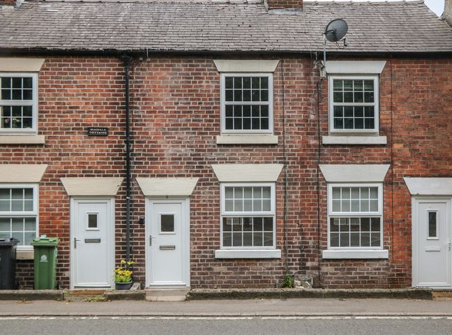 A row of brick cottages with white doors and windows on a street at Magdala Cottages