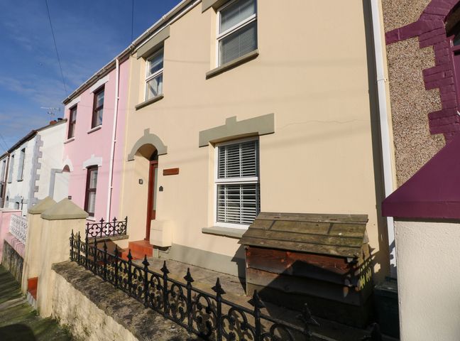 A row of terraced houses with iron fencing and a wooden box in front at Stones Throw in Tenby
