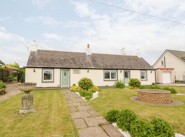 A single story cottage with two green doors two chimneys and a garden with a pathway and bushes at Braeface Cottage in Banknock near Bonnybridge