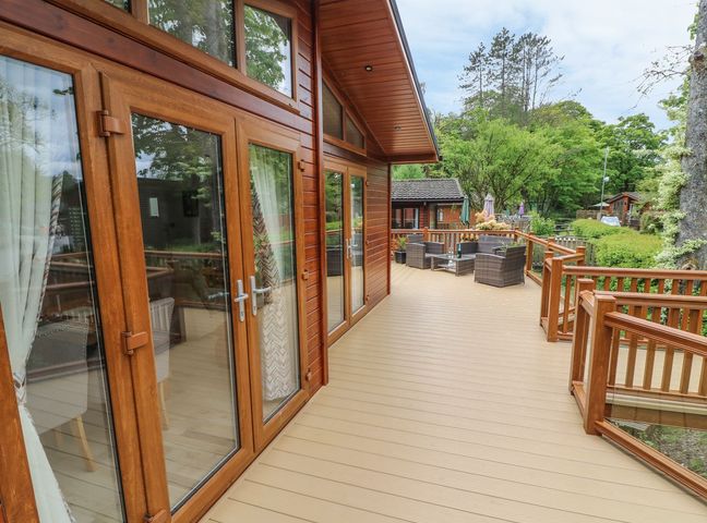 A wooden deck with patio furniture and glass doors at 8 Waterside Wood in White Cross Bay near Troutbeck Bridge