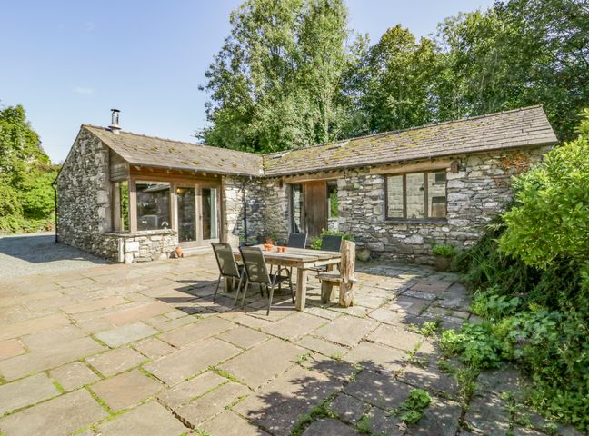 A stone cottage with a patio table and chairs outside at Egg Pudding Stone in Field Broughton near Cartmel