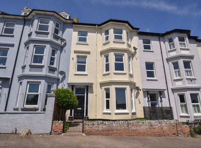 A row of three-story terraced houses with bay windows and small front gardens at Flat 2 10 Seafield Road in Seaton