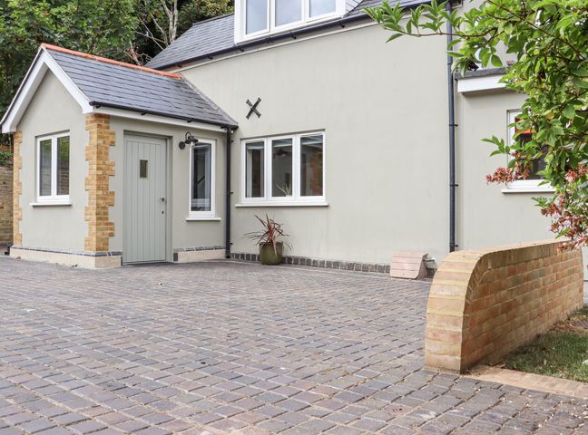A cobblestone driveway next to a beige house with white framed windows and a light grey door at 24 Elm Grove in Westgate-On-Sea