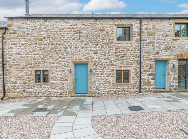 A stone exterior of a house with two blue doors and small windows at No 2 The Coach House in Thornton In Lonsdale