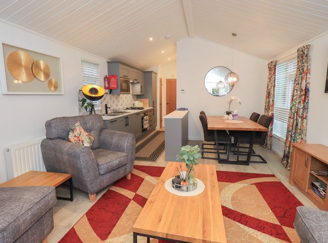 A living room with a sofa and dining area at Merewood in Troutbeck Bridge