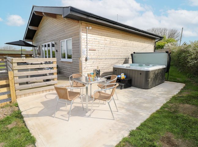 An outdoor area with a hot tub and seating at Monks Rest in Monknash