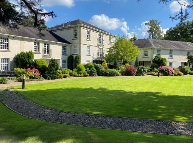 A courtyard with a lawn and garden in front of residential buildings at Lakeside View in Lakeside near Bowness-On-Windermere