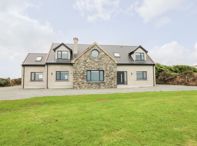 A two story house with stone and beige exterior walls and a grass lawn at Old Field House Slade near Fethard-On-Sea County Wexford