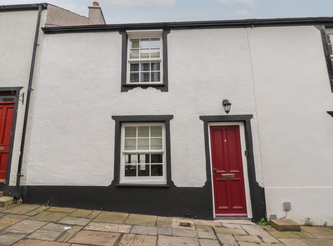 A white house with black trim around windows and a red door numbered 4 at Neptune Cottage in Conwy