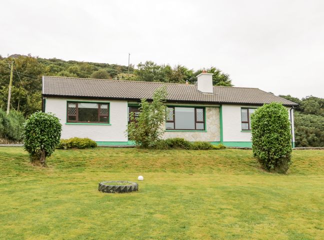 A single story house with white walls and green trim with bushes and grass in front at Drumore House Laddan near Carrigart County Donegal