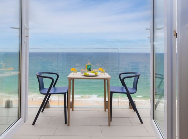 A balcony with a table and two chairs overlooking the ocean at Wavetop in Carbis Bay