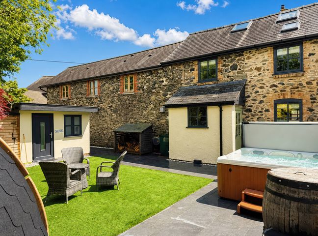 A garden with chairs and a hot tub at Railway Cottage in Penybontfawr