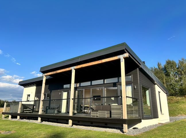 A house with a deck and glass railing at Osprey View Lodge & Hot Tub Aberfeldy