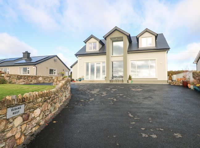 The front view of a two-story house with a large driveway and stone walls at Robins Rest in Ballyhack County Wexford
