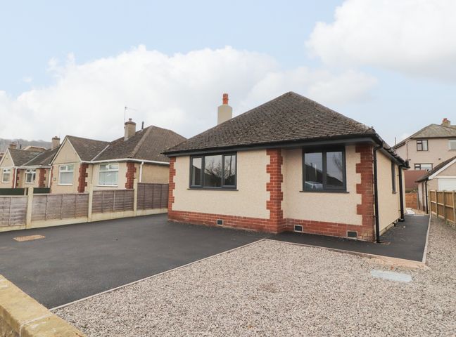 A detached bungalow with two large windows and a gravel and asphalt driveway at 12 Merefell Road Bolton Le Sands