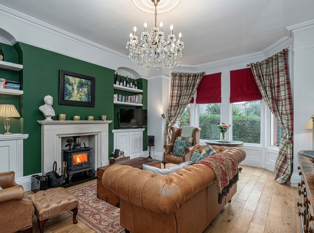 A living room with a fireplace leather sofas and a chandelier at No 22 in Llandudno